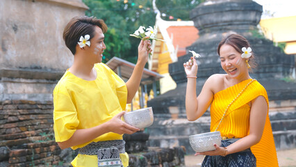 Couple wearing traditional Thai clothes happy playing songkan During the Songkran festival of...