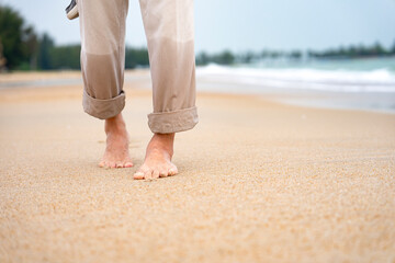 senior man legs slowly barefoot walking on sand beach,elderly lifestyle,relaxing,foot massage for...