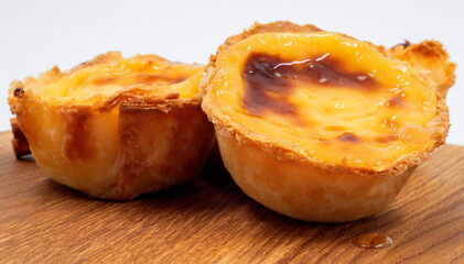 Pastel de nata tarts or Portuguese egg tart on a wooden brown background. Pastel de Belem is a small pie with a crispy puff pastry crust and a custard cream filling. Sweet dessert.