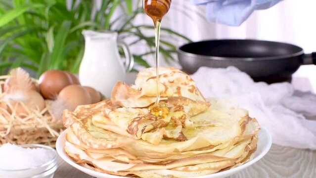 Season freshly baked homemade thin pancakes on a plate with honey. One of a series of video recipes. circle of rotation, close-up, slow motion