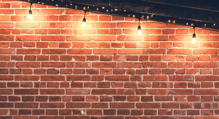 Lights garlands hanging from red brick wall at evening.
