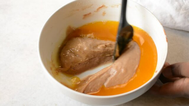 Mixing Melted butter and Madeleine batter in a white mixing bowl