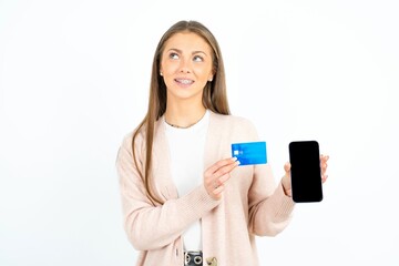 Fototapeta premium Young beautiful woman holding bank card modern device looking empty space