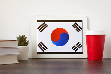 National flag of South Korea on the tablet, textbooks, a red cup of hot drink coffee or tea on the...