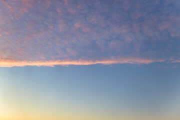 A beautiful sky tinted by the sun leaving vibrant shades of gold, pink, blue and multicolored. Clouds in the twilight evening and morning sky. Cloudy sky background in the evening and during the day.