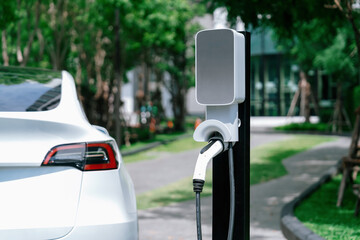 EV electric car charging in green sustainable city outdoor garden in summer. Urban sustainability...