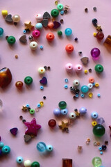 Various colorful beads on bright pink background. Top view.