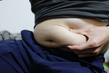座っている中年男性のお腹の脂肪 - obrazy, fototapety, plakaty
