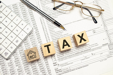 tax with house symbol word on wooden blocks with calculator and pen. Property tax concept