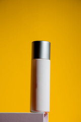 Cosmetic product in tube, bottle, lotion or serum on yellow background