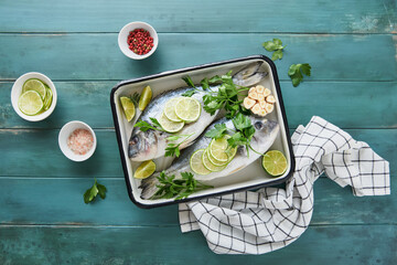 Raw fresh. Fresh raw dorado with lemon, lime, parsley and salt on old wooden blue background ready...