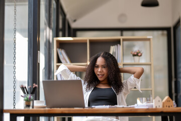 Black businesswoman stretching lazy at the desk to relax while working in the office. Feeling stressed and achy from work.