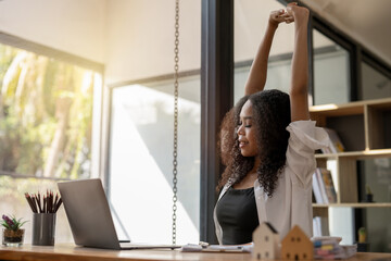 Black businesswoman stretching lazy at the desk to relax while working in the office. Feeling...