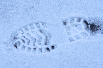 one trace with a pattern from the sole of a shoe on white snow on a winter street