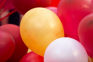 Colorful balloons on red and white background, close-up.