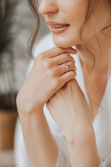 Hands of the bride in a white wedding dress with a gold wedding ring with a diamond close-up....
