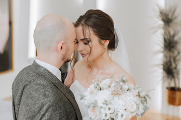 The bride is dressed in an elegant lush white wedding dress with a long veil and is ready for her groom. The first meeting of the bride and groom