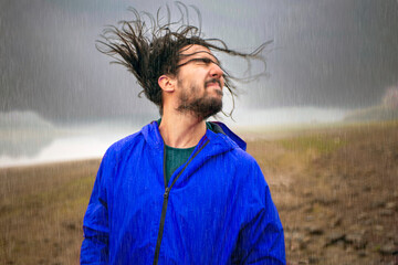 Man standing in pouring rain shaking his head in enjoyment