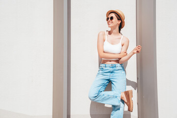 Beautiful smiling model in sunglasses. Female dressed in summer hipster white T-shirt and jeans....