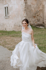 Obraz premium A beautiful bride runs with a long train. The bride in a white dress with a long train in nature on a summer day. Summer wedding.