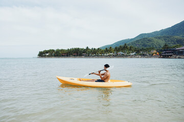 Active Asian Man Having Fun Kayaking on Tropical Beach