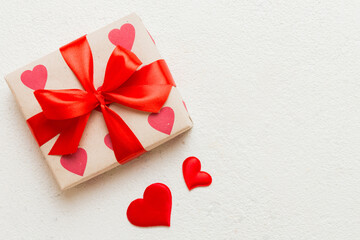 Top view photo of valentine day decorations gift box with red ribbon bow on colored background....