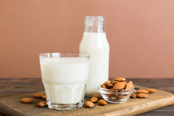 Top view of the almond milk in the glass bottle with almond nuts on the colored table. top view vith copy space