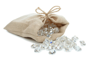 A linen pouch filled with sparkling diamonds on a white backdrop