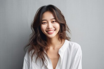 Fototapeta premium Asian girl with perfect skin and long, luxurious hair poses against a white backdrop, epitomizing beauty and simplicity. Generative AI.