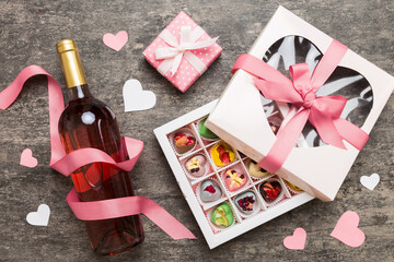 Fototapeta na wymiar Bottle of red wine on colored background for Valentine Day with gift and chocolate. Heart shaped with gift box of chocolates top view with copy space