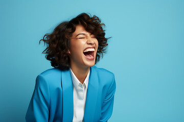 a happy young lady with a blue background laughing