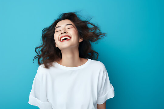 a happy young lady with a blue background laughing