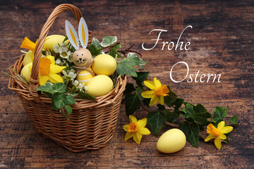 Osterkarte: Korb mit gelben Ostereiern einem lustigen Osterhasen und der Text Frohe Ostern.