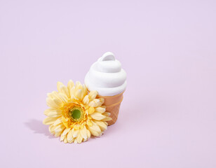 Summer holiday and vacation composition. White ice cream in a waffle cup and a nice smelling yellow flower.