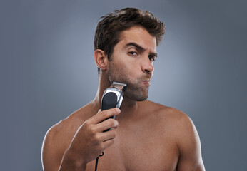 Man, shaving and machine in studio for beard grooming, skincare and portrait by grey background....