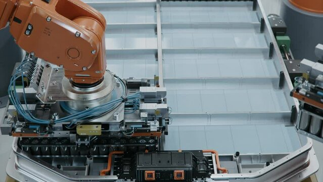Robot Arm Installing Battery Module into the Frame. EV Battery Pack for Automotive Industry Assembly. Electric Car Smart Factory. Battery Manufacturing Line. Automated Production Line.