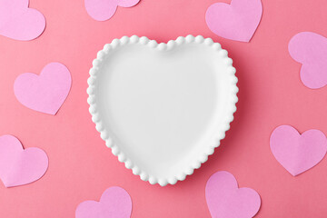 Heart shaped plate with pink hearts on a red background. Valentines day gift. Top view