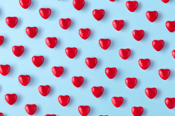 Red hearts pattern on blue background. Top view.