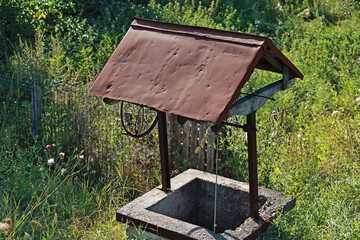 Naklejka premium Traditional Romanian fountain with a tin roof in the countryside.