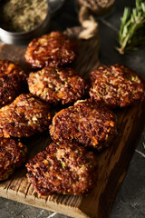 Beef, zucchini and cheddar cheese patties or cutlets on wood board. Low key food photo, dark background. Dinner meat concept, full of proteins. 