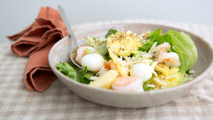plate with salad with shrimp, pineapples and quail eggs on the table