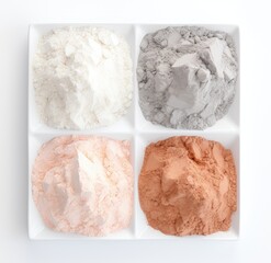 A white tray filled with powders in four different colors; blue, green, yellow, and red.
