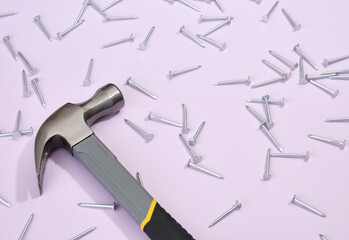 Iron nails scattered on the table, hammer with rubber grip for nailing. Copy space for text.
