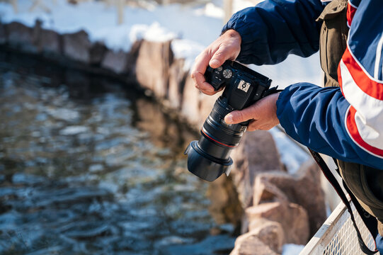 photographer's hand with modern dslr camera photographing nature in winter close-up
