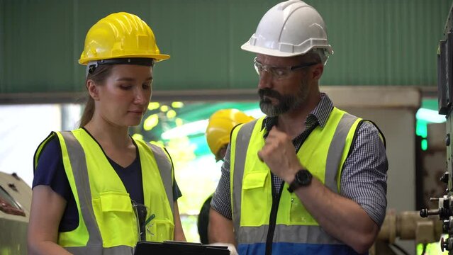 group of Two engineer man and technician worker repair machine discuss with tablet in steel metal manufacturing factory plant industry. team maintenance check quality machine. training explain work