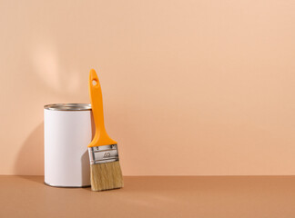 Paint brush and paint can on a beige background. Copy space for text. Repair in apartment.