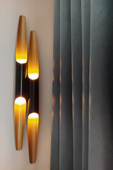 Two modern sleek wall lights casting warm glow beside elegant dark gray curtains