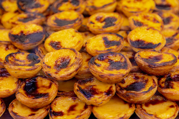 Stack of Portuguese egg tart (Pasteis de Nata) display in front of shop, A delicious local favourite dessert with pastry shell, Sweet tarts with an aromatic custard that gets baked and scorched on top