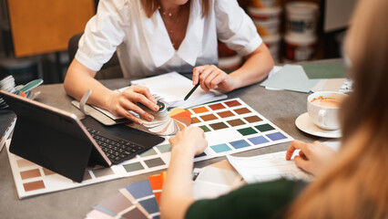 Close up hand choosing color from color sample swatch. The designer works with the customer and...
