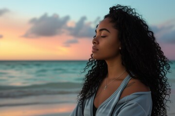 A young black woman with long curly hair doing yoga on the beach